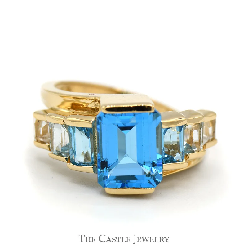 Men’s Designer Engagement Rings-Emerald Cut Blue Topaz Ring with Graduated Design in 14k Yellow Gold Bypass Setting